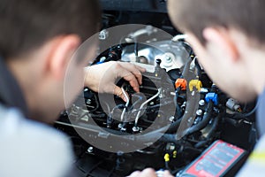 Mechanics at repair shop. two confident mechanics working on a car engine