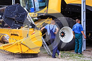 The mechanics repair the yellow Combine harvester in the farm ya