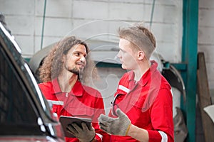 Mechanics in uniform with tablets working in auto service, Young Caucasian car mechanics with a checklist, Technician checking