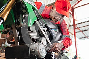 Mechanics wear wearpacks and caps using a wrench to tighten the motorcycle bolts