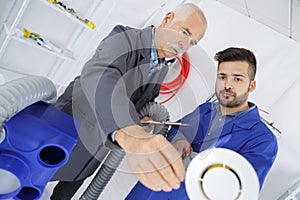 mechanics working on ventilation pipe in workshop