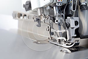 Mechanism of an industrial overlock sewing machine - closeup view on foot and needles with blurred background