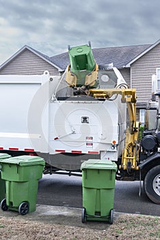 Mechanized Garbage Truck Dumping Trash From Residential Barrel