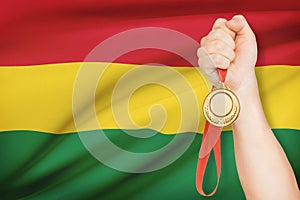 Medal in hand with flag on background - Plurinational State of Bolivia