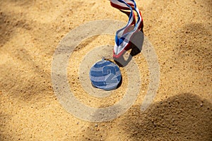 Medal lying on the yellow sand, beach volleyball competitions. Second place, silver