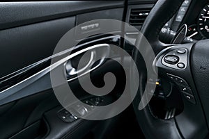 Media control buttons on the steering wheel in black perforated leather interior with computer monitor. Modern car interior detail