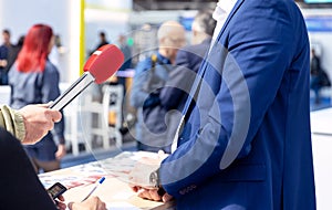 Media interview with a businessman at a publicity event. Business person is giving an economic outlook to the journalist.