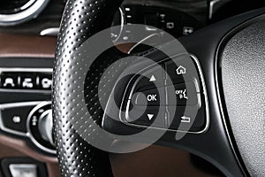 Media and navigation control buttons on a steering wheel of a Modern car. Car interior details. Brown leather interior of the luxu