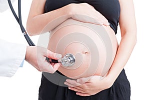 Medic listening pregnant woman belly using stethoscope