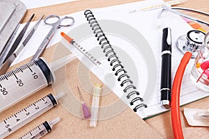 Medical accessories with blank notebook on the wooden table.