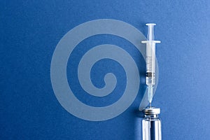 Medical ampoule and syringe on a blue background.