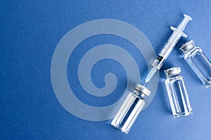Medical ampoule with vaccine on blue background