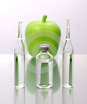 Medical ampoules and a bottle with an apple on a white background. Natural remedies