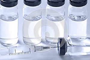 Medical ampoules with vaccine and syringe on white background