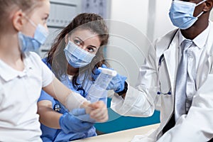 Medical asisstant helping african american pediatrician doctor to bandage broken arm