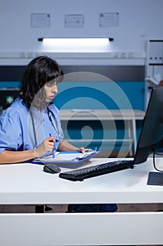 Medical assistant analyzing documents and files on monitor