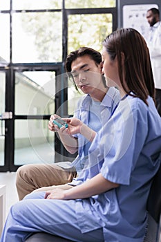 Medical assistant consulting asian patient with glucometer while measuring insulin and glucose level