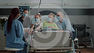 Medical assistant explaining diagnosis to patient and family in hospital ward