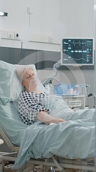 Medical assistant looking at heart rate monitor while patient sleeping
