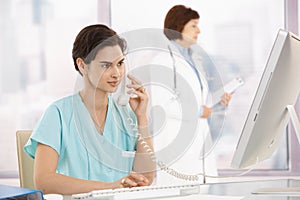 Medical assistant on phone, using computer