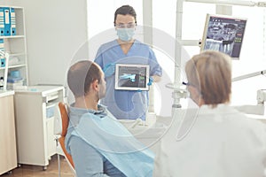 Medical assistant reviewing tooth x ray to sick patient