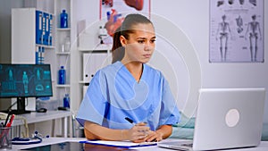 Medical assistant typing on laptop and taking notes on clipboard