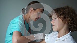 Medical assistant woman inoculating a curly boy. Flu vaccination, immunization plan. Medicine and healthcare concept