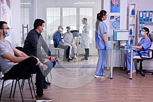 Medical assistants talking in hospital reception wearing protection masks