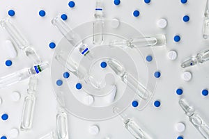 A medical background from ampoules for injections and small blue and white psychotropic tablets. photo