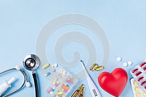 Medical background from pharmaceutical tablets and pills, stethoscope, heart and thermometer top view. Healthcare and medicine