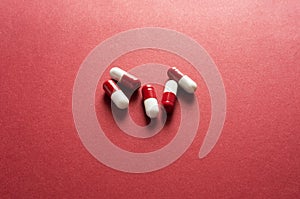 Medical background, red-white capsules on a red background. Top view of pills on red surface
