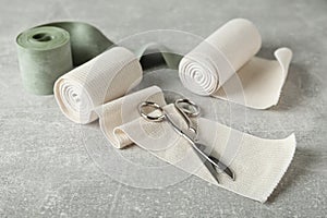 Medical bandage rolls and scissors on grey table