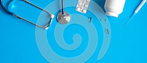 Medical banner design with pediatric doctor equipment on blue background. Top view table with stethoscope, pills and syringe.