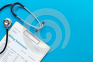 Medical billing statement with stethoscope. Top view photo