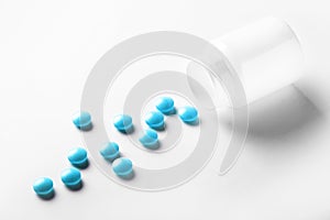 Medical blue pills and white bottle on white light background. Concept of healthcare and medicine.