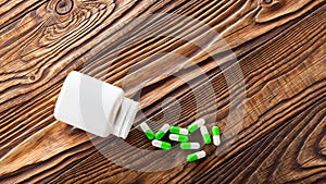 Medical blue pills and white bottle on wooden background.