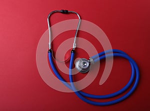 Medical blue stethoscope isolated on red background