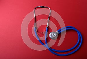 Medical blue stethoscope isolated on red background