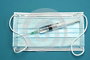 Medical blue white facemask with vaccine needle on a empty copy space background