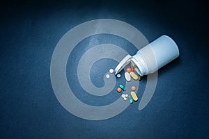 Medical bottles and medication pills spilling out on to pastel blue background. Top view with copy space. Healthcare, pharmacy