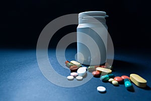 Medical bottles and medication pills spilling out on to pastel blue background. Top view with copy space. Healthcare, pharmacy