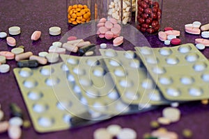 Medical bottles and medication pills spilling out on to purple background