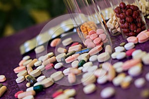 Medical bottles and medication pills spilling out on to purple background