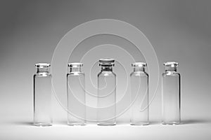 Medical bottles test tubes black and white photo stand on a gray background five in a row transparent glass containers