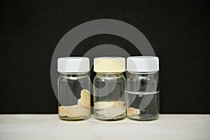Medical bottles with wisdom molar teeth removed, on white surface on isolated black background. Maxillofacial surgery
