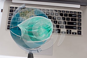 Medical breathing mask that protects the globe from viral epidemic on background with laptop