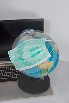 Medical breathing mask that protects the globe from viral epidemic with laptop on white background