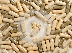Medical capsules on beige top view. One capsule opened to show a powder. Dietary supplements