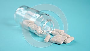 Medical capsules in a glass pharmaceutical bottle on a blue bright table close-up