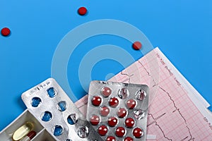 Medical cardiology concept. Heart health pills and cardiogram on a blue background. ECG. Copy space